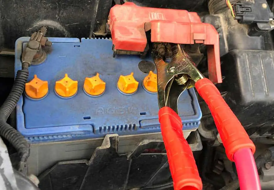 red jumper cable connected to jumper car's battery