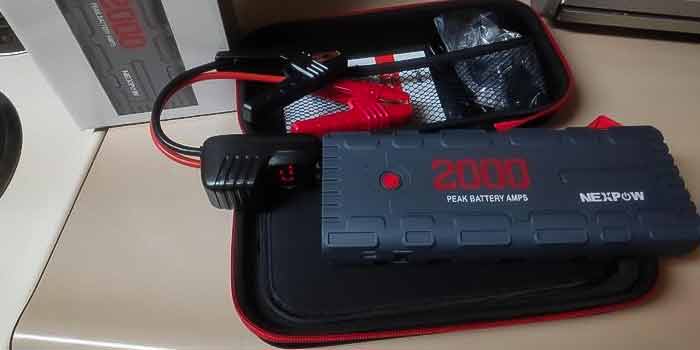 NEXPOW 2000A jump starter sitting on top of carrying case with all items that come in the box when purchased